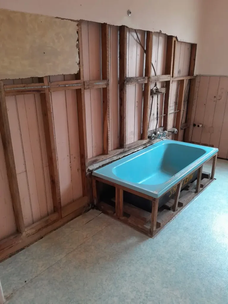 Older bathroom with asbestos wall lining removed back to the timber boards