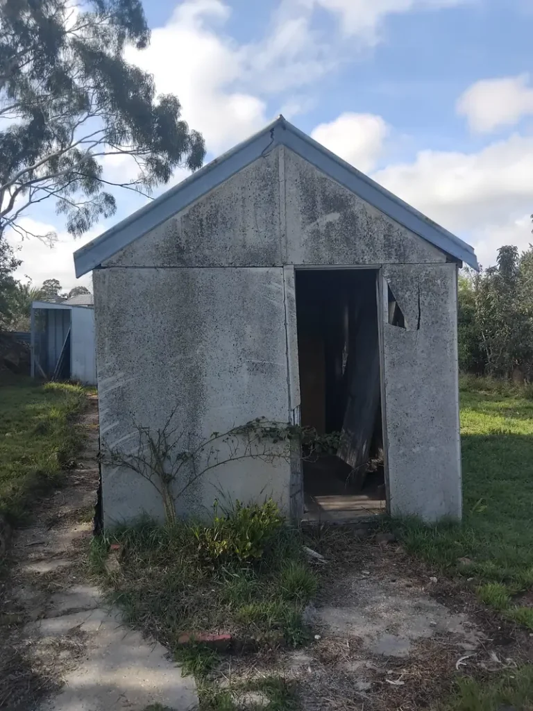 Weathered fibro shed with cracked asbestos cement sheeting