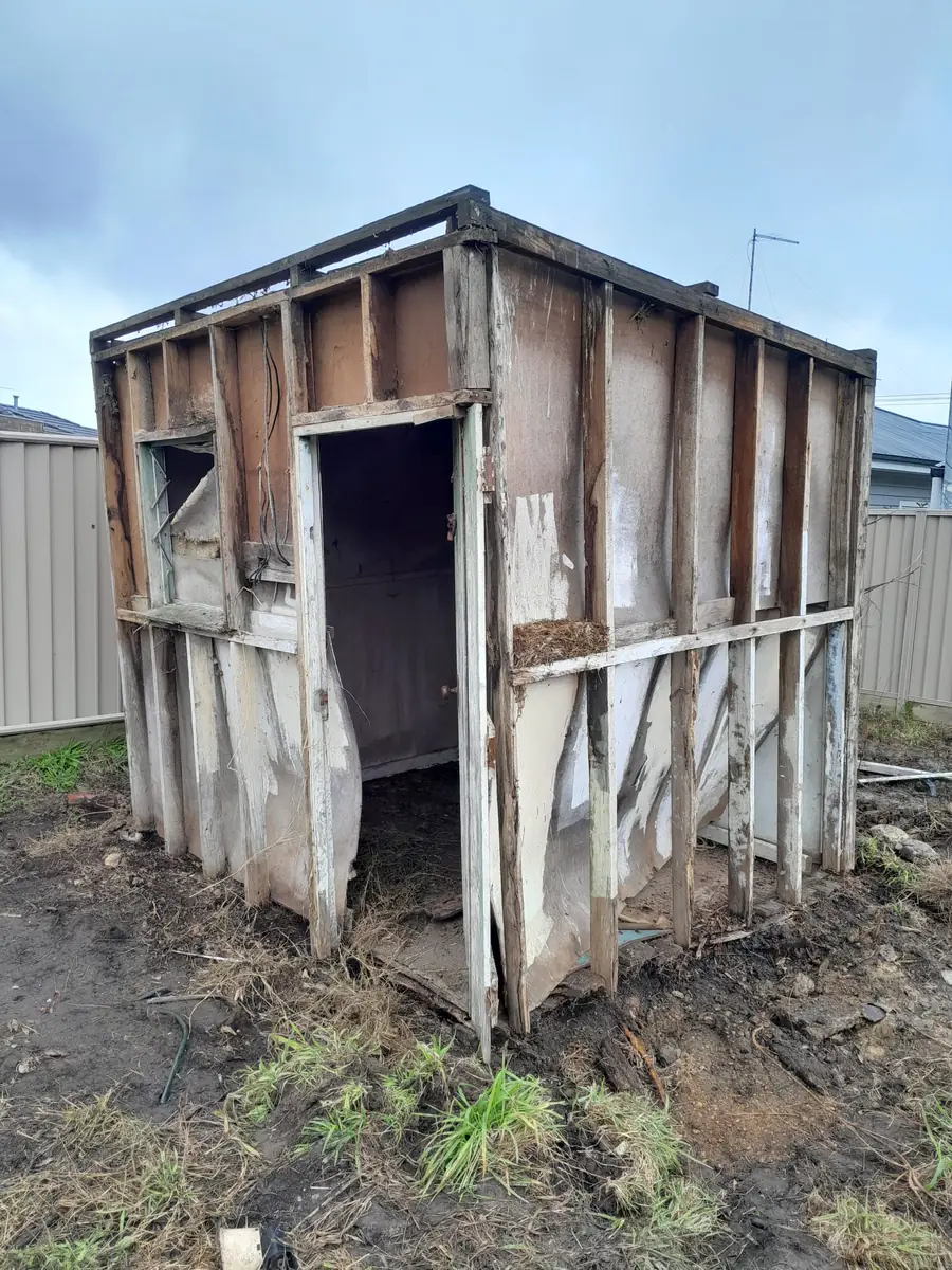 Old backyard shed with damaged fibro cement sheeting before demolition