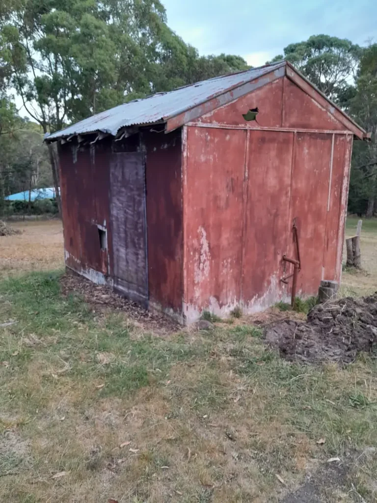 Painted fibro shed on a rural property before asbestos removal